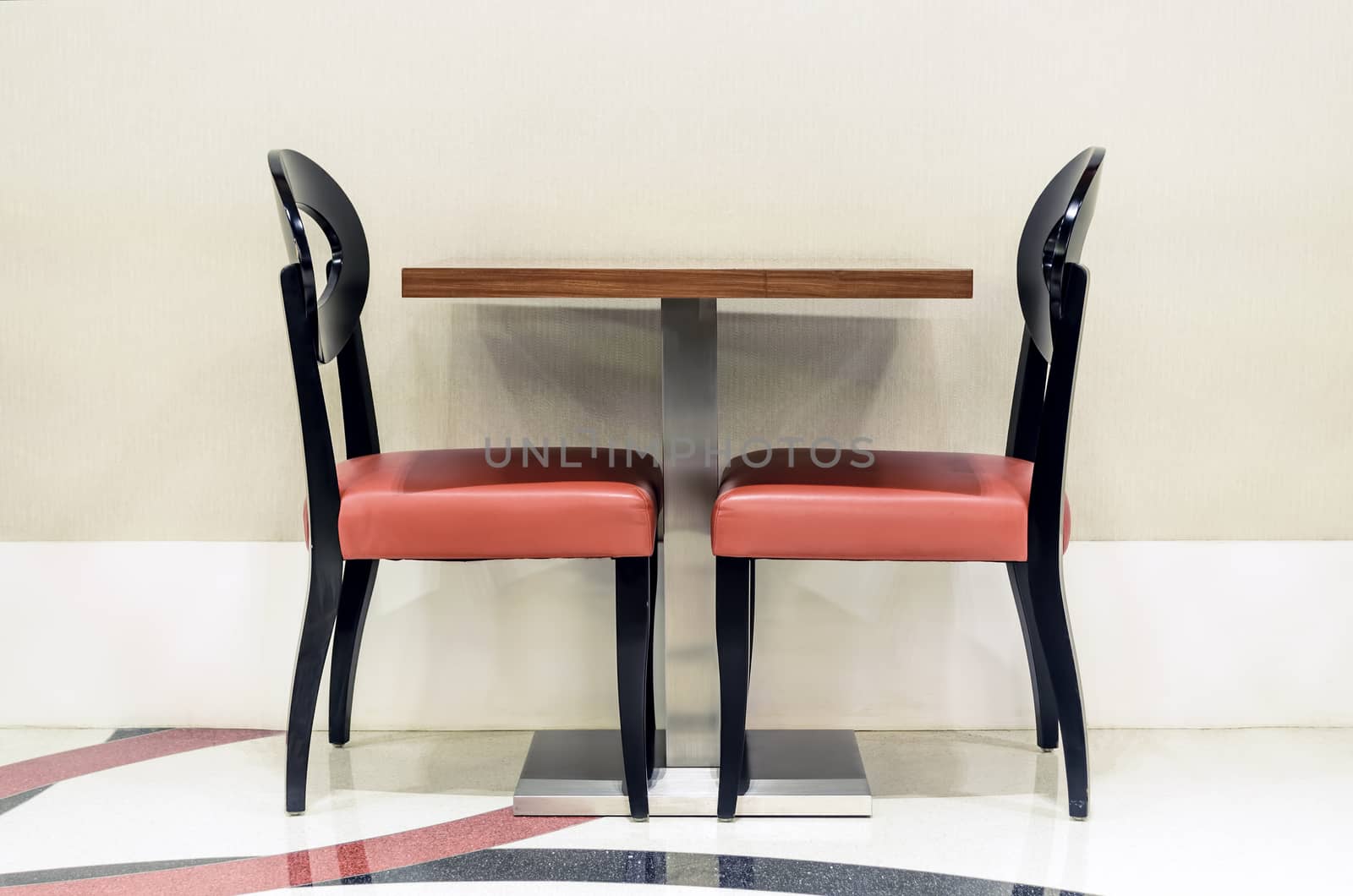 Two unoccupied red restaurant chairs by the wall