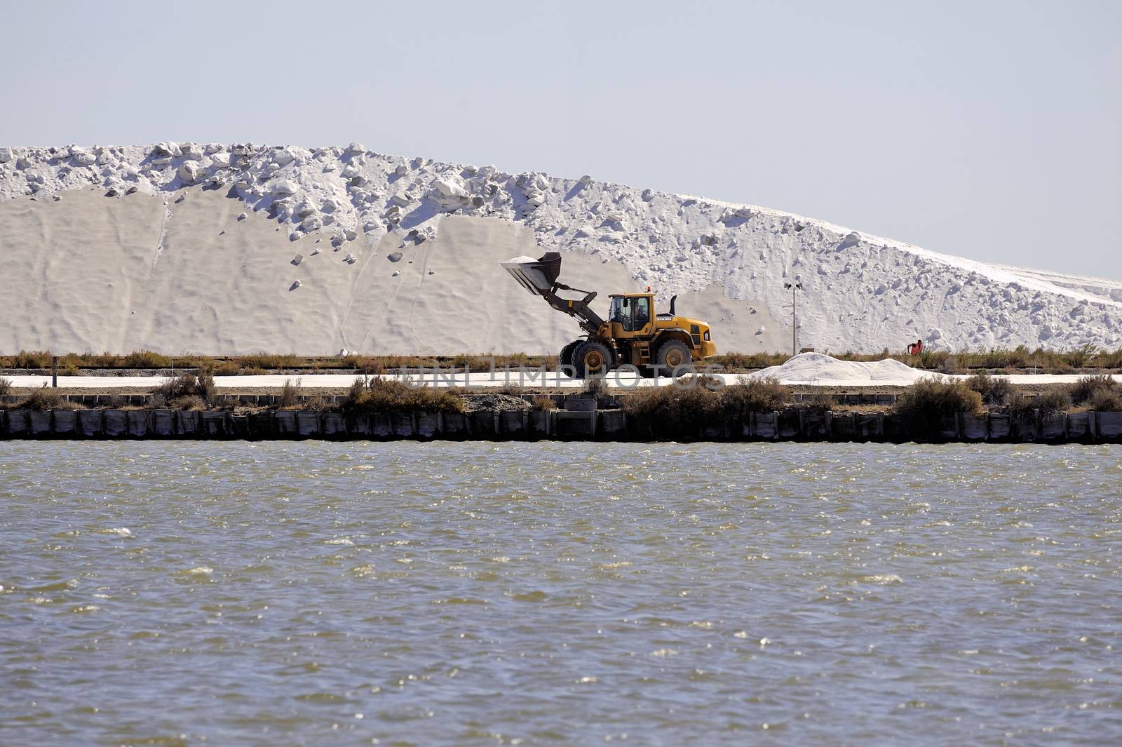 Site operating sea salt saline Aigues-Mortes with big machines and trucks working for the salt storage