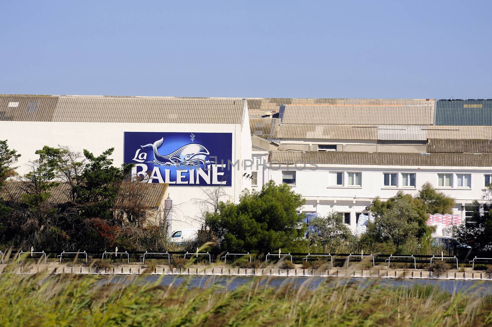 The buildings of the industrial enterprise saline Aigues-Mortes in Camargue with the panel in the name and the logo of the brand.