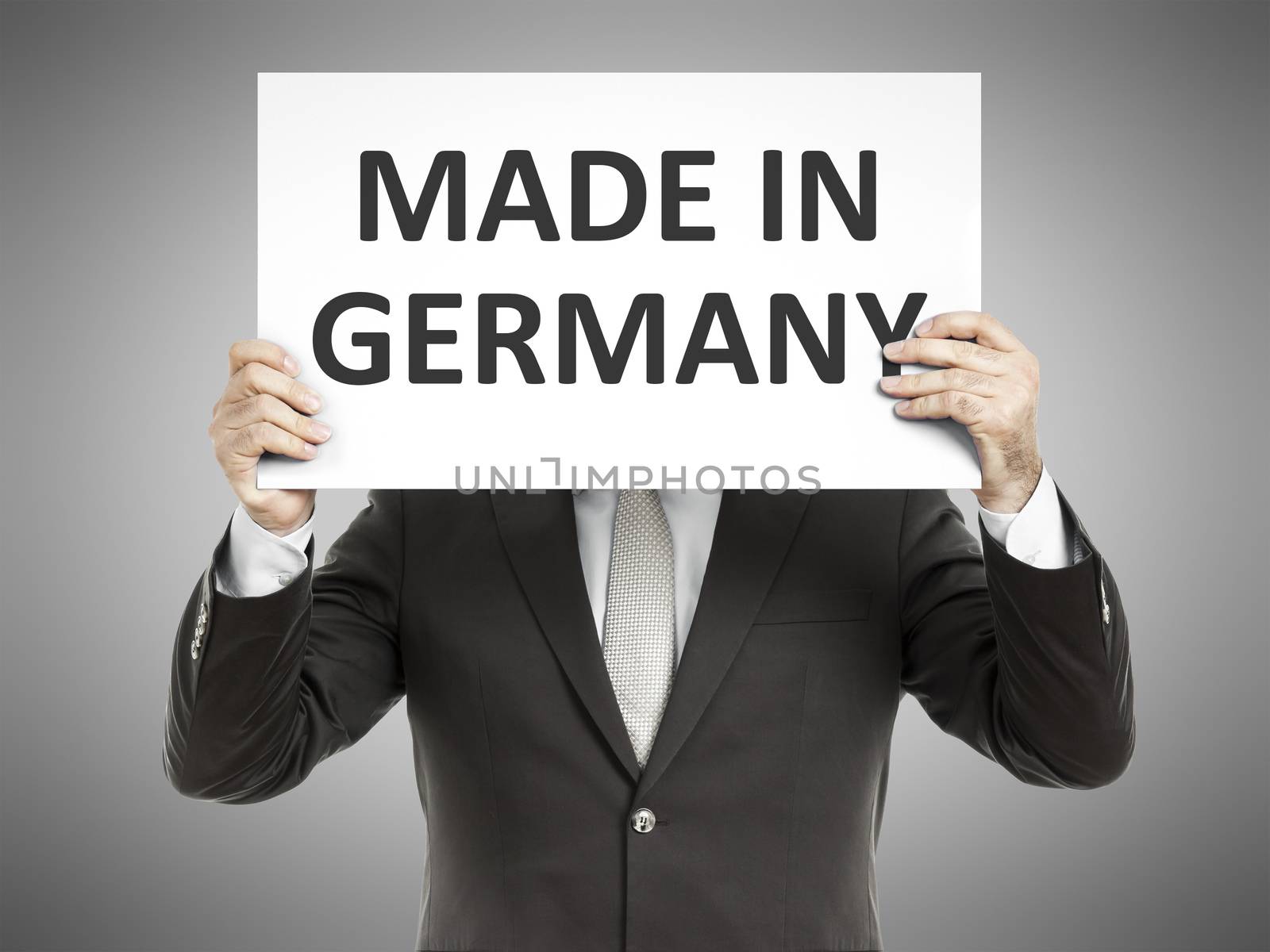 A business man holding a paper in front of his face with the text made in germany