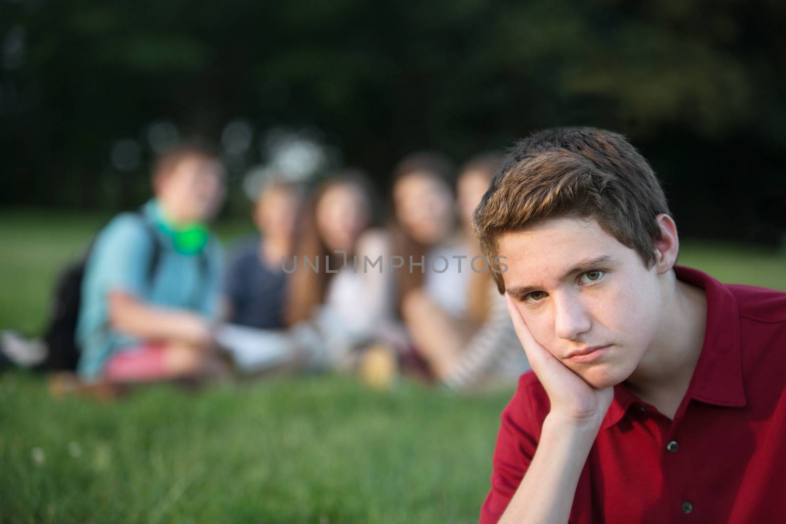 Lonely male teenager sitting with hand on cheek