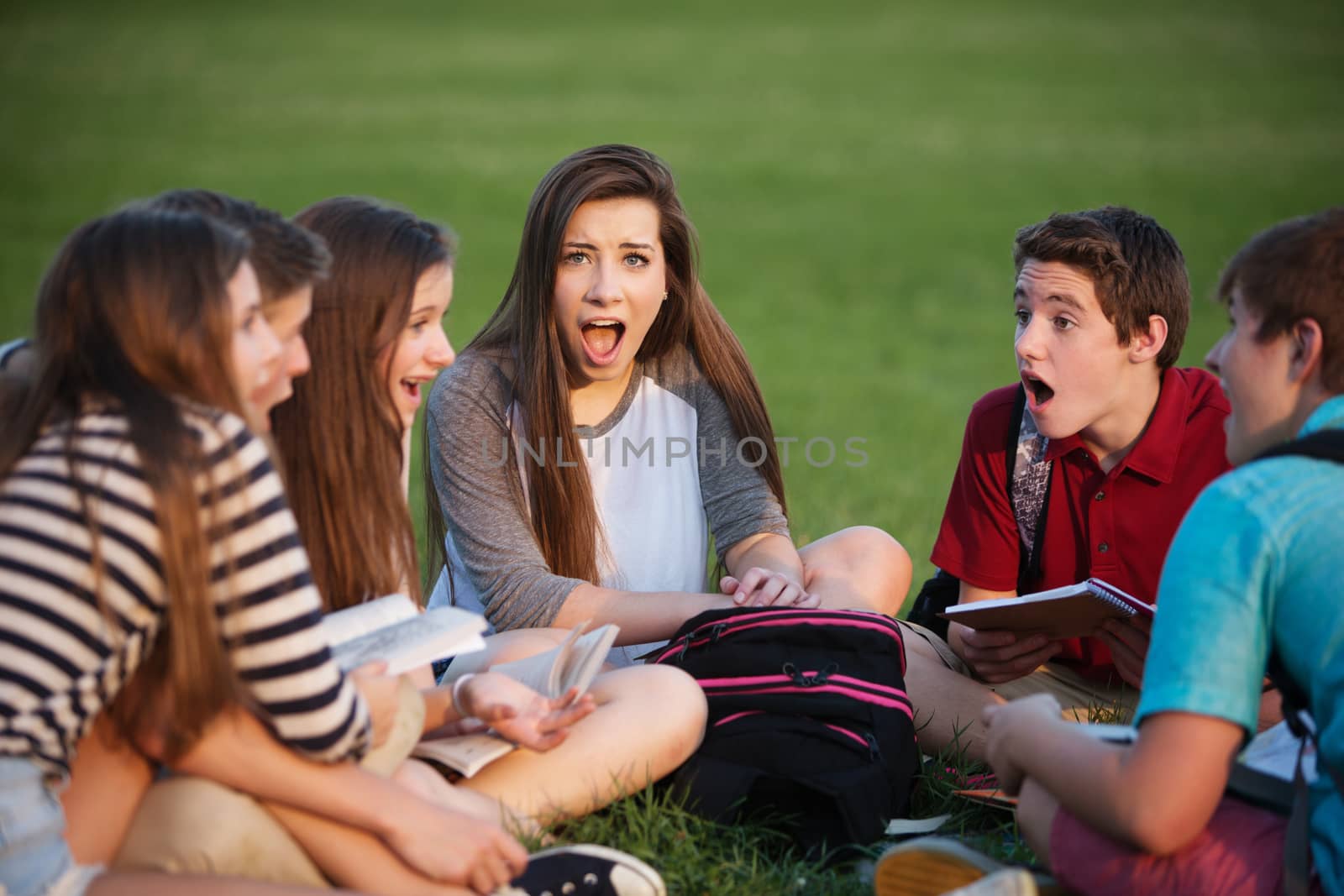 Shocked female teenage student sitting with friends