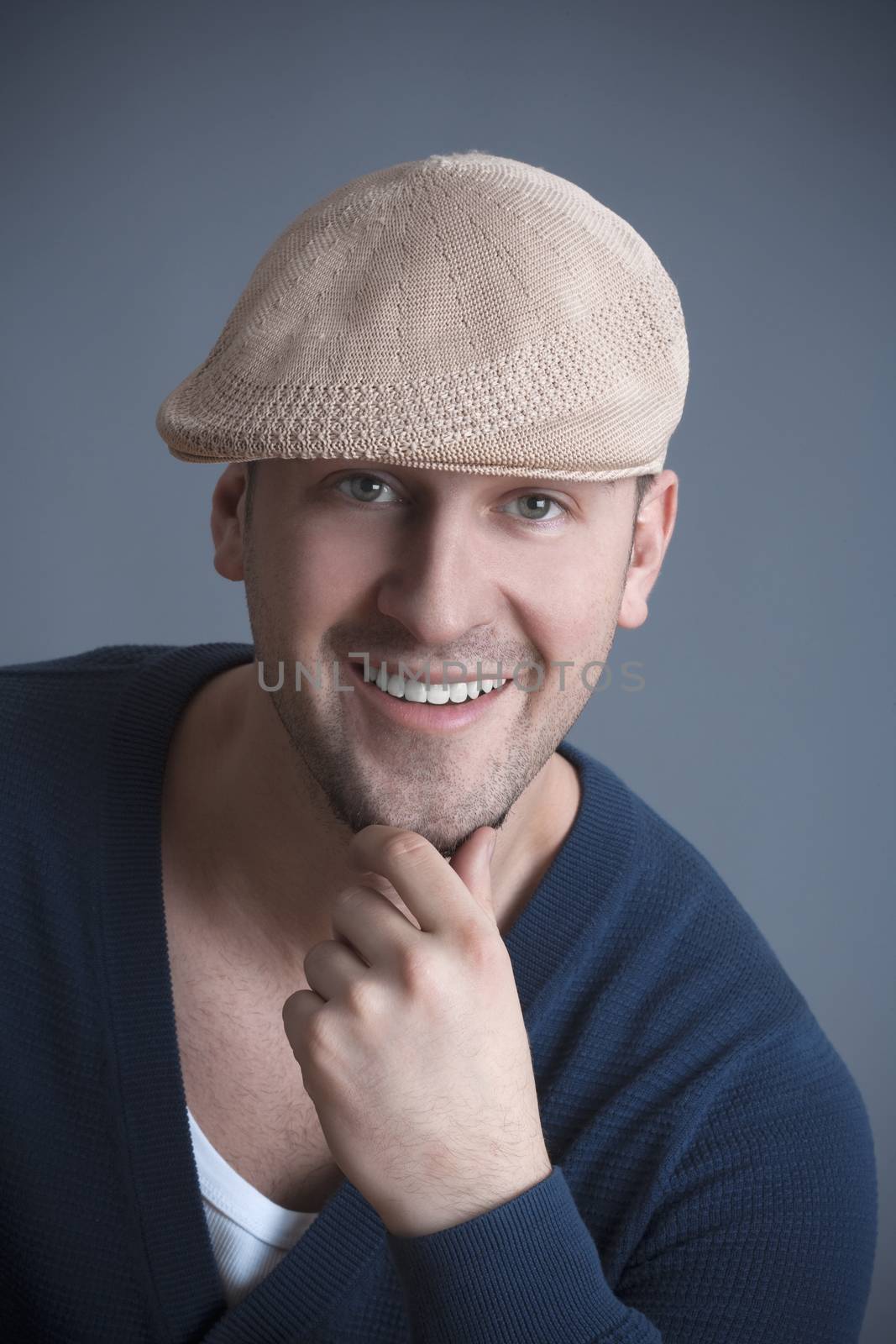 studio portrait of a young handsome man with cap, smiling