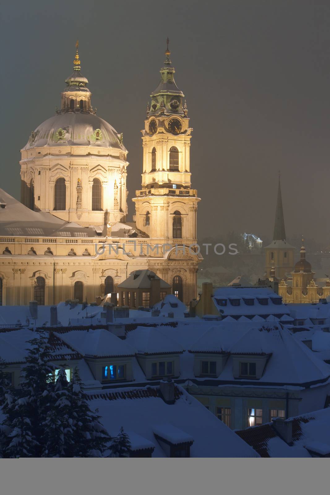 prague - view of snowy rooftops and st. nicolaus church in winter