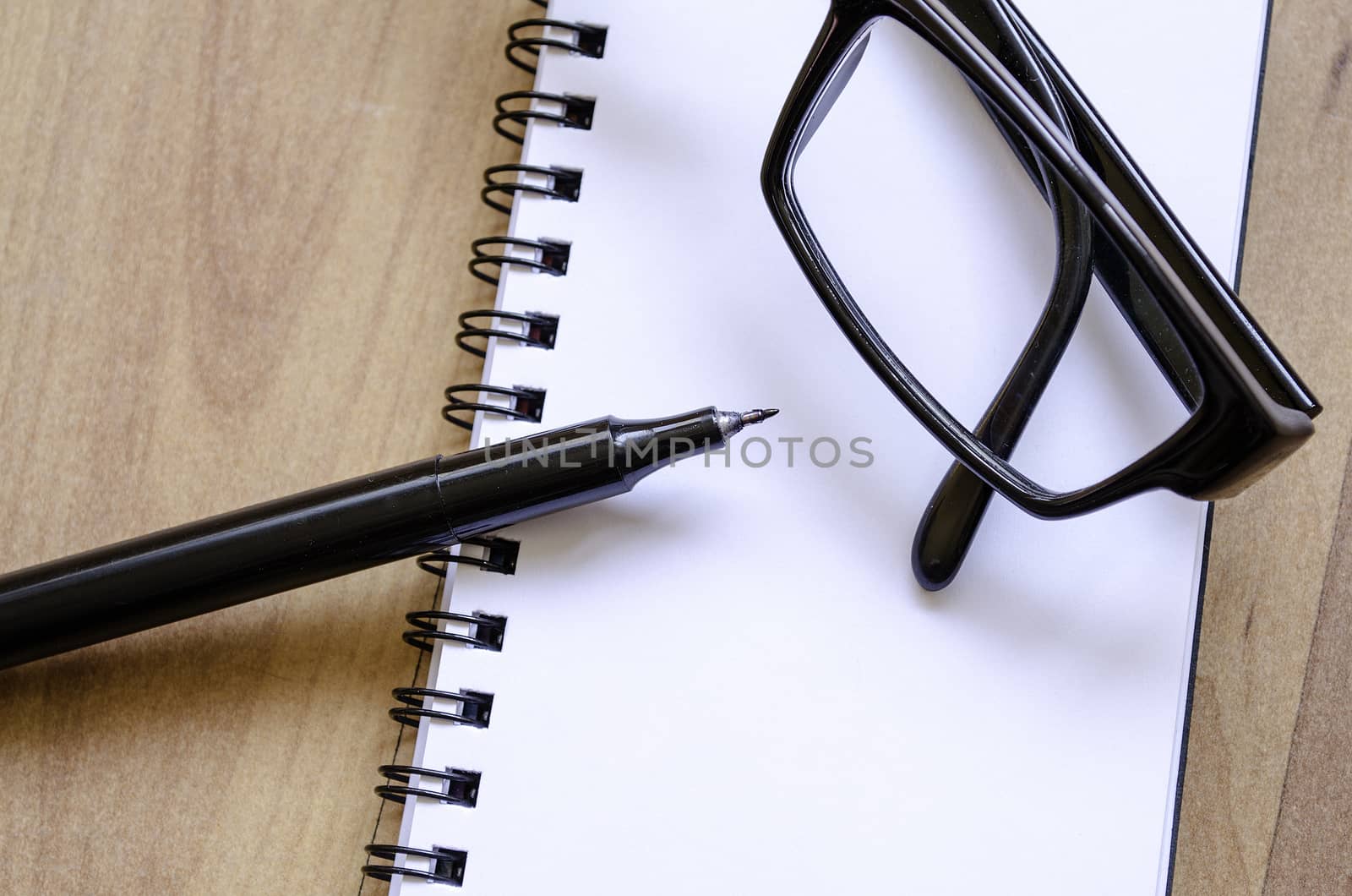 White notepad,glasses and ink pen on the wooden desk