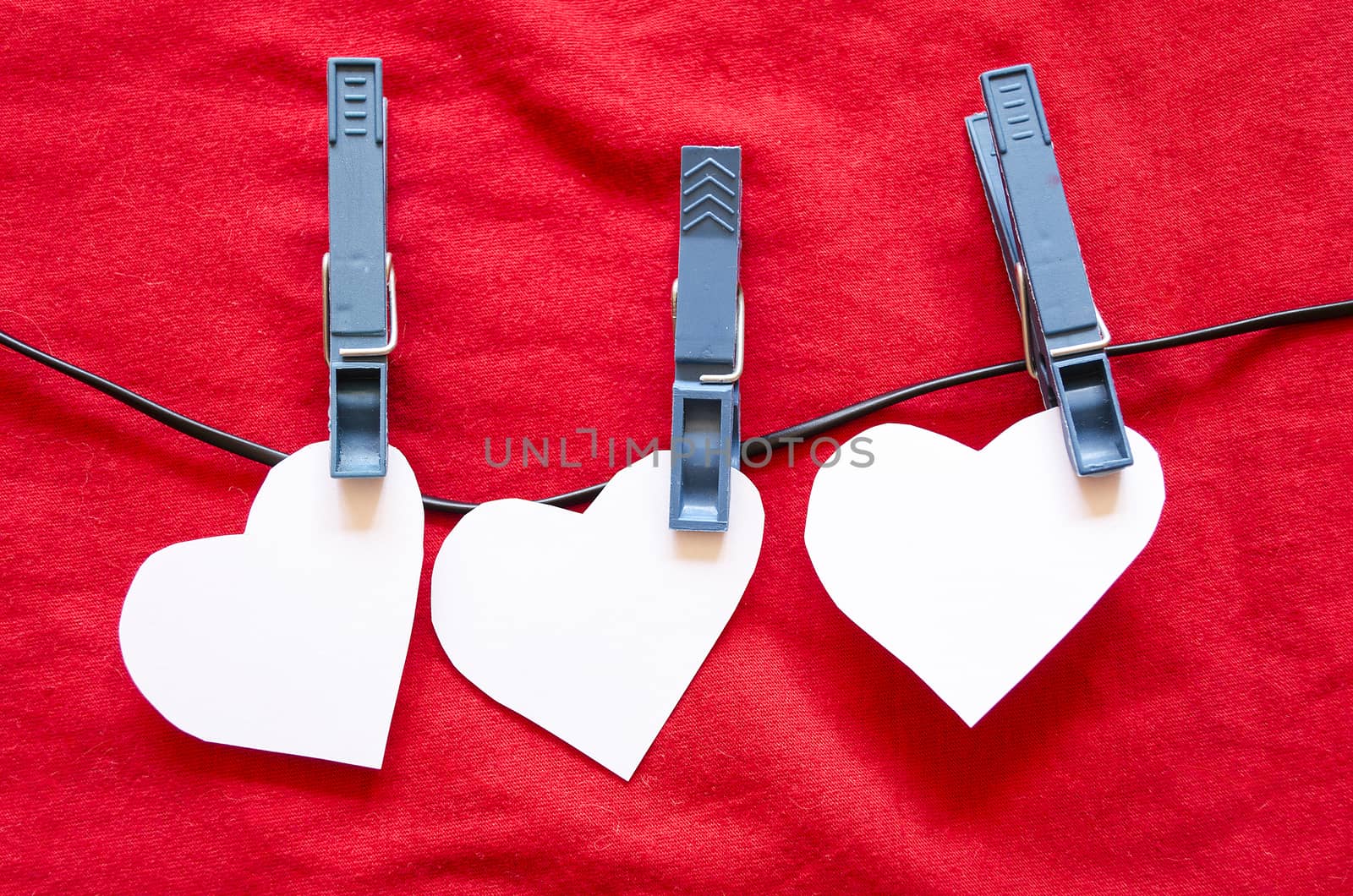 Three Paper Hearts on a Clothesline on a Textured blue Background.