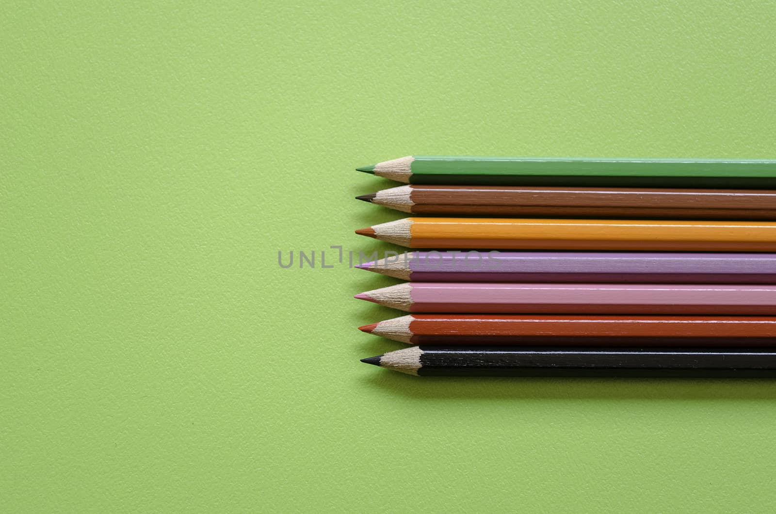 Colorful pencil crayons on a green background, back to school