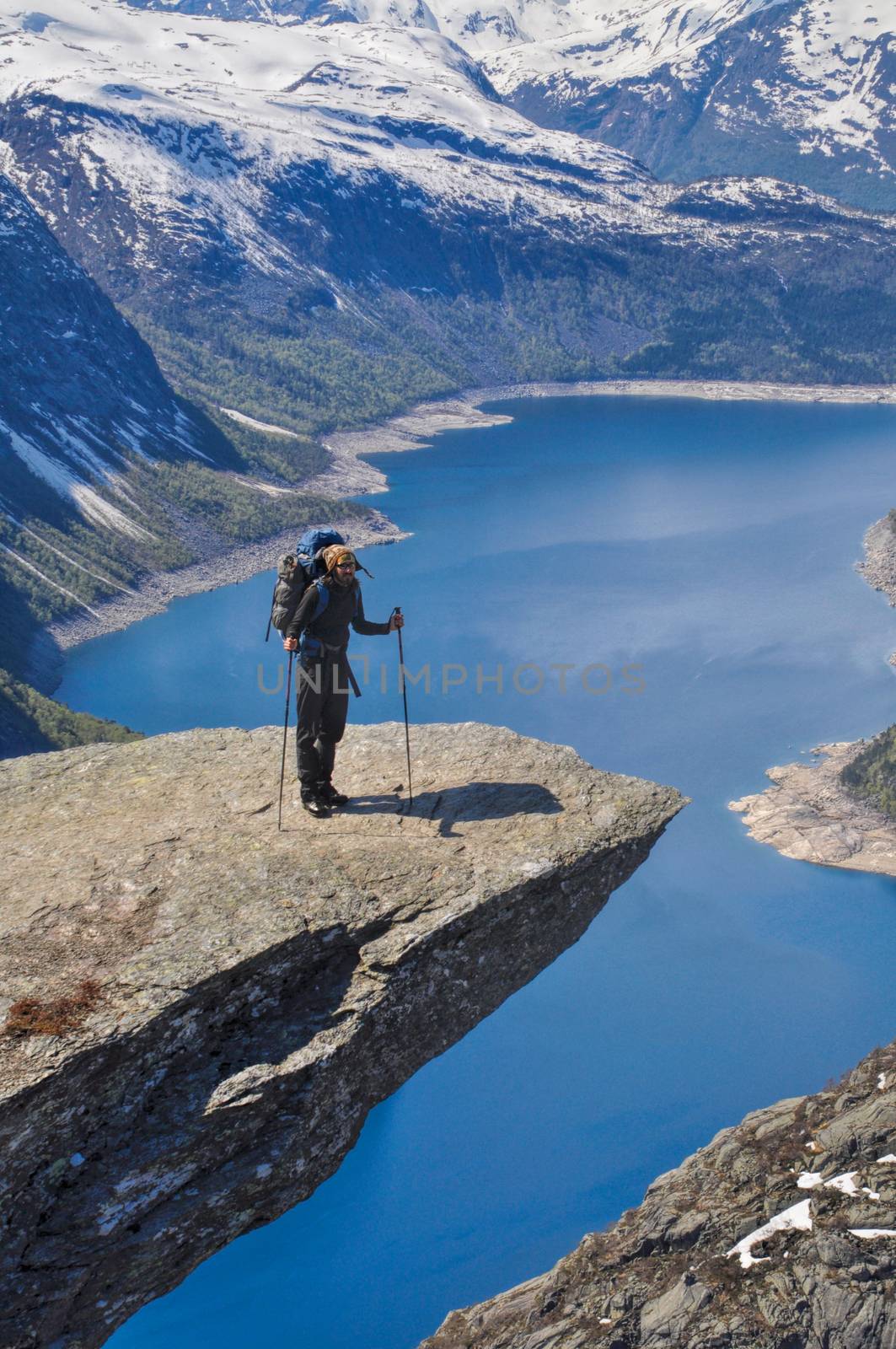 Hiker taking a break at the top of Trolltunga rock in Norway