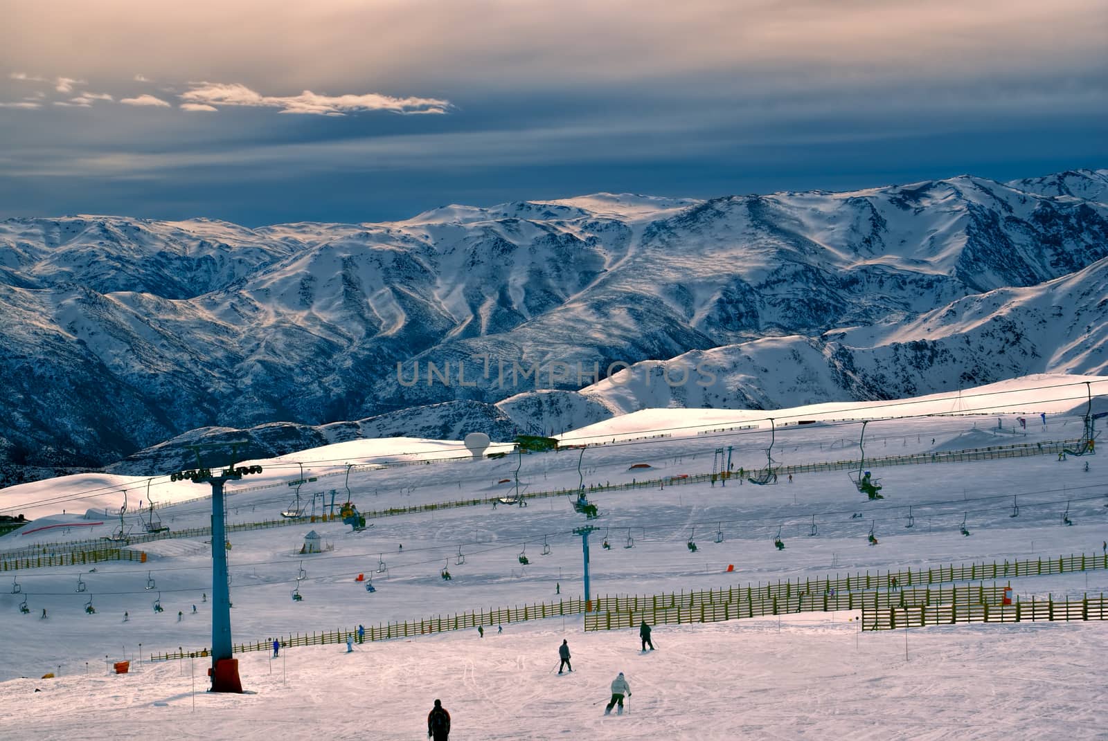 Breathtaking view of skiers and beautiful mountains at sunset in Valle Nevado