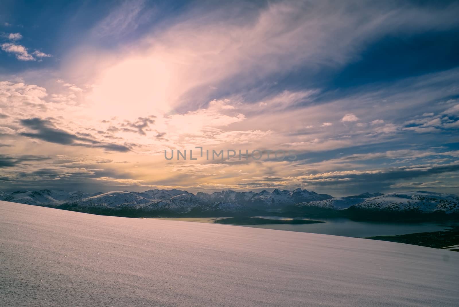 Picturesque view of snowy plain and mountains at sunset in Tromsdalstinden              