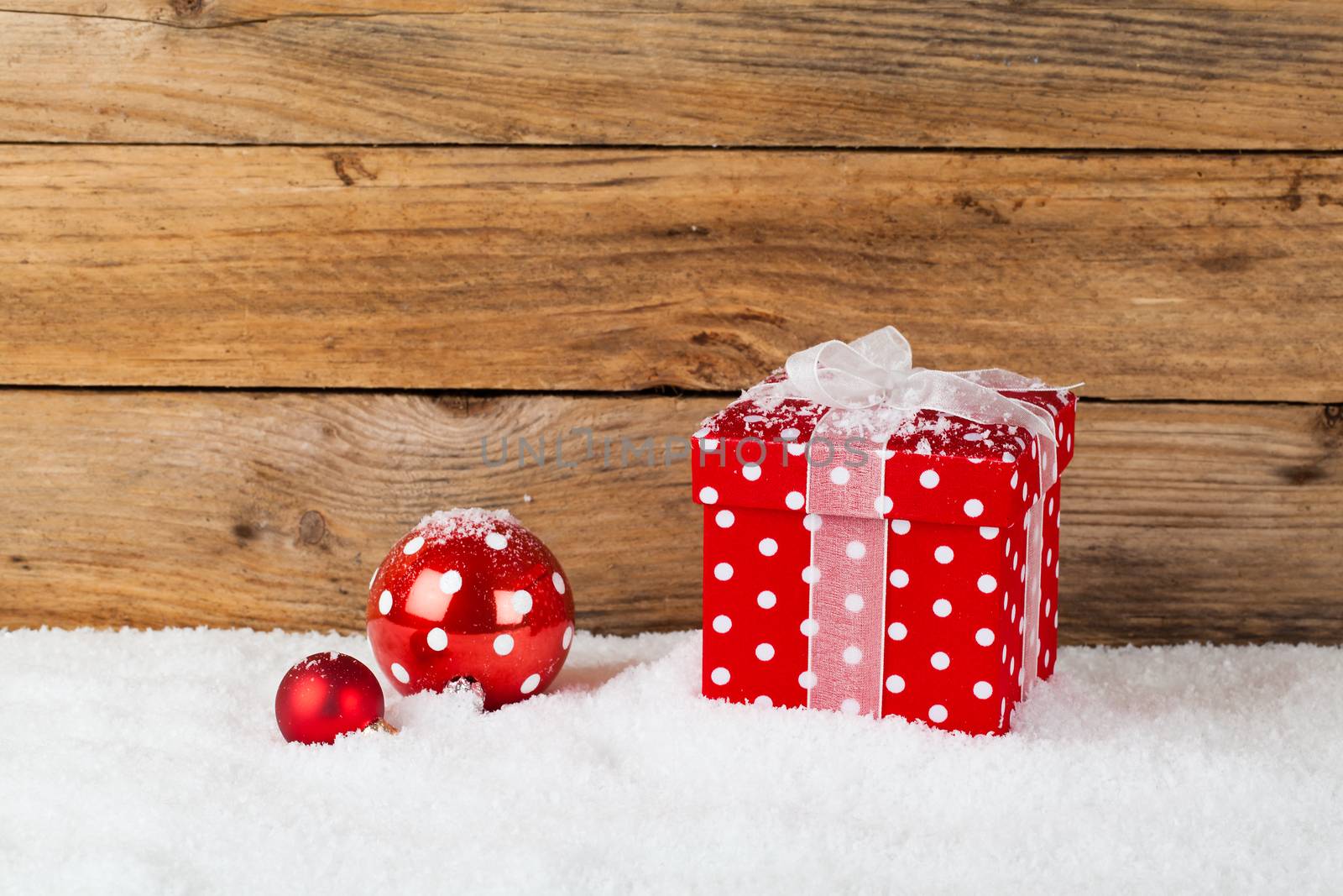 christmas red gift with snow, on wooden background