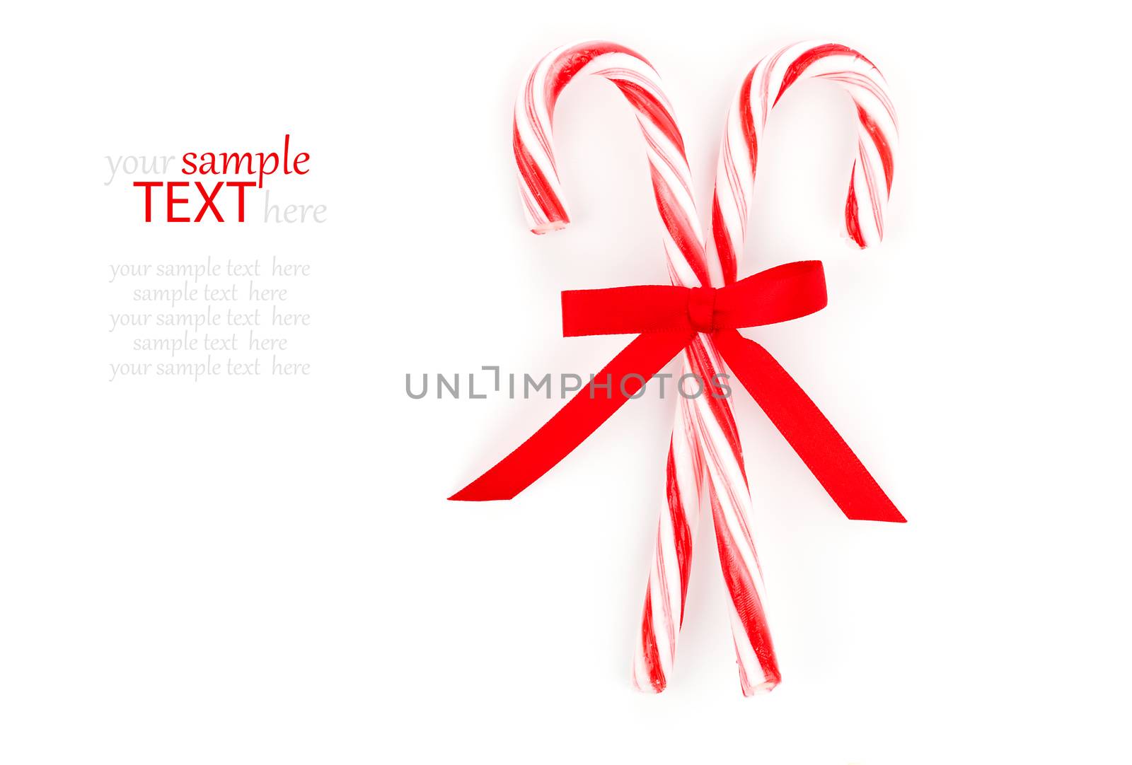 Close up of two candy canes tied with ribbon bow on white background