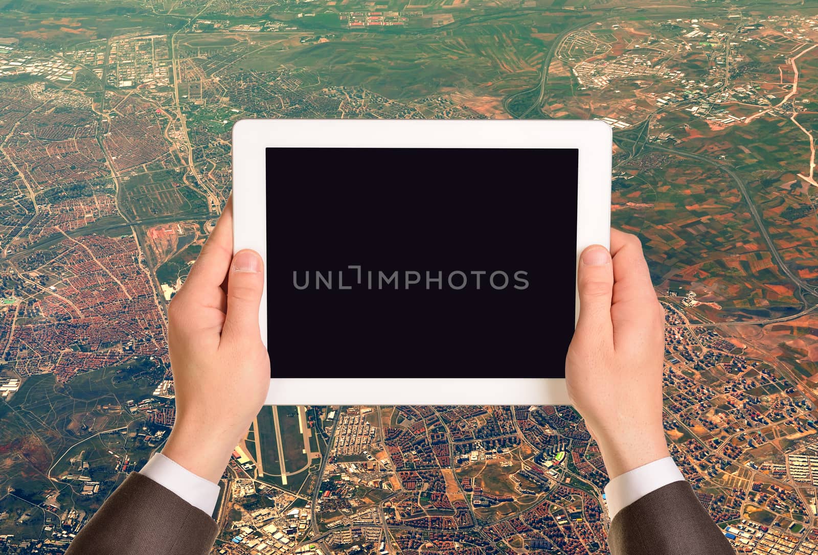 Hands holding tablet pc with empty screen. Aerial view of cityscape