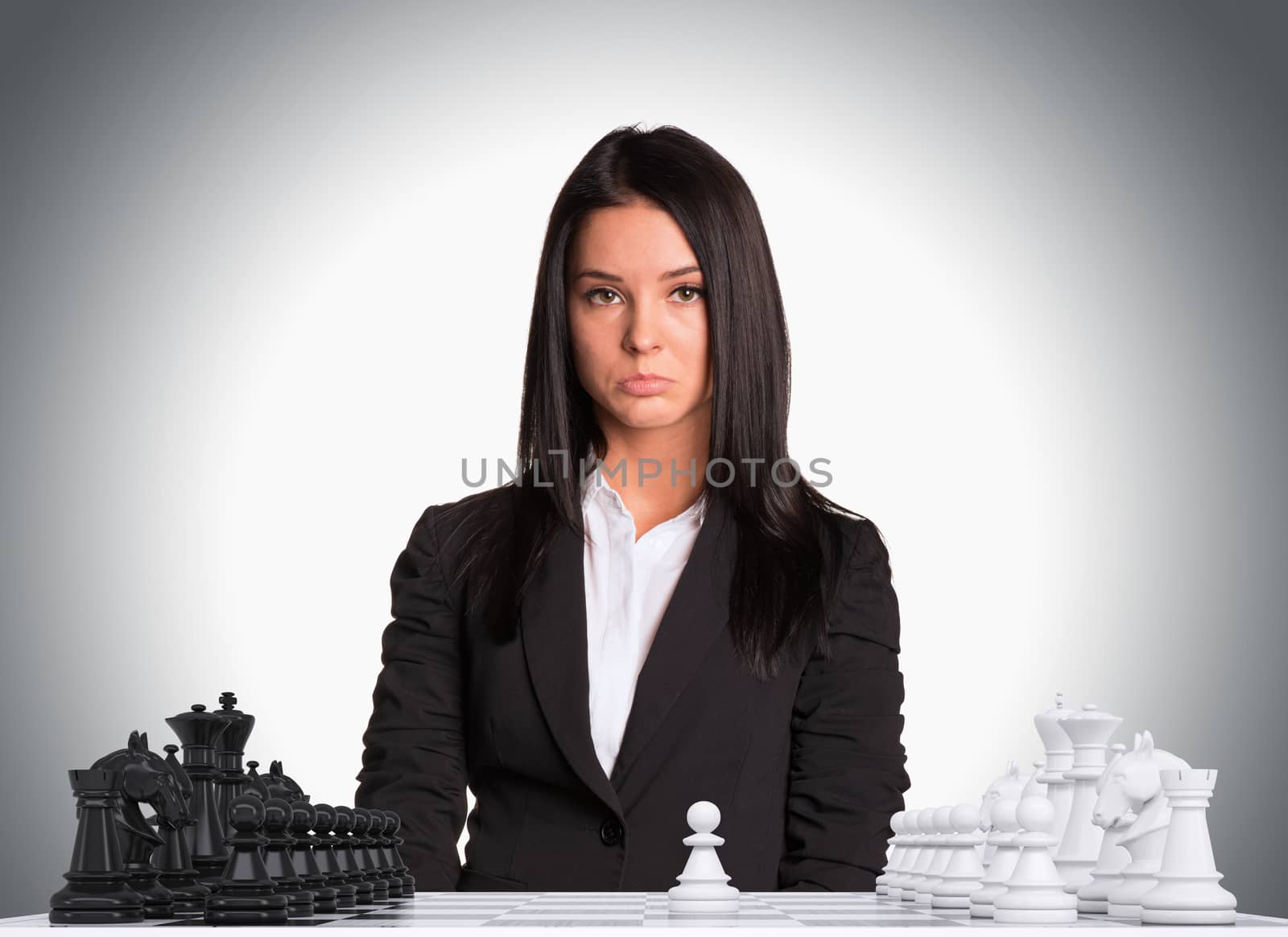 Upset businesswoman looking at camera. Chessboard with chess. Gray background. Business concept