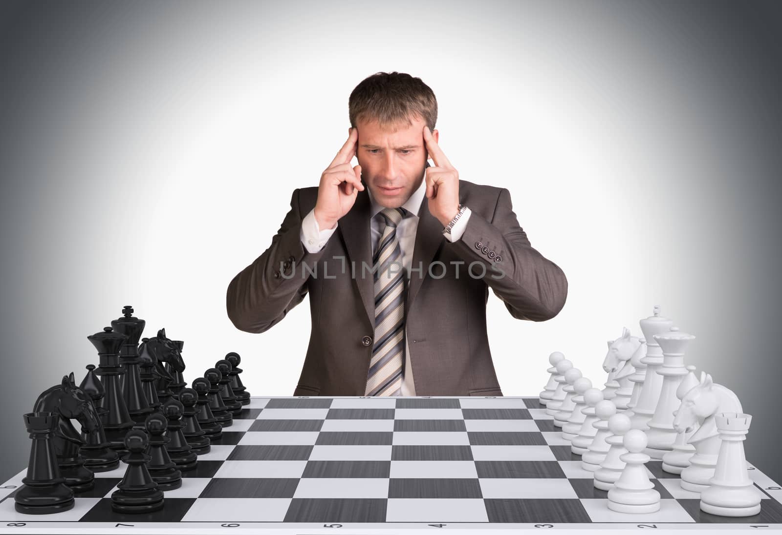 Lost in thought businessman and chess board with chess. Gray background. Business concept