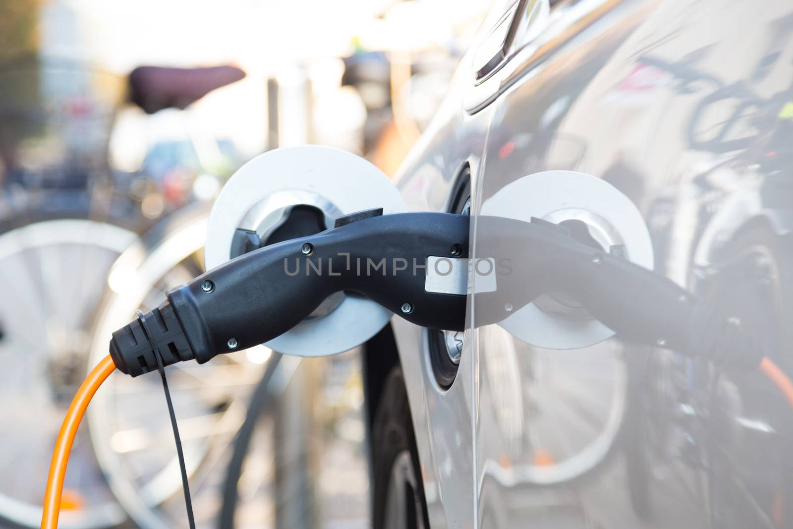 Power supply for electric car charging.  Electric car charging station. Close up of the power supply plugged into an electric car being charged.