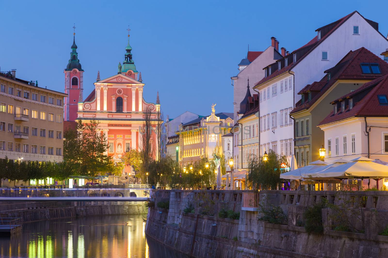 Romantic medieval Ljubljana's city center, capital of Slovenia, Europe. Night life on the banks of river Ljubljanica where many bars and restaurants take place. Franciscan Church in background