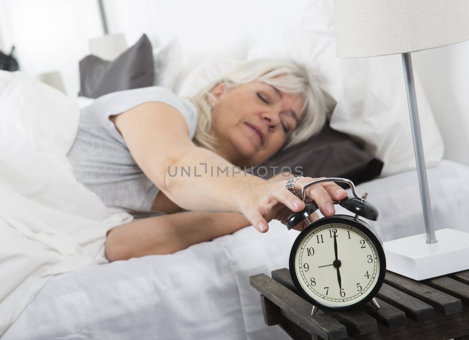 Sleeping woman turn off the alarm clock