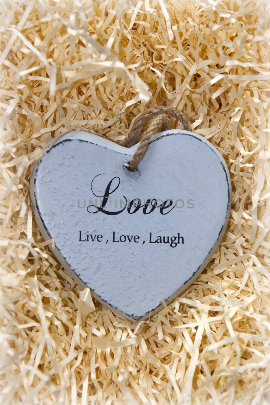 single grey wooden love heart in a love nest made of straw inscribed love, live and laugh