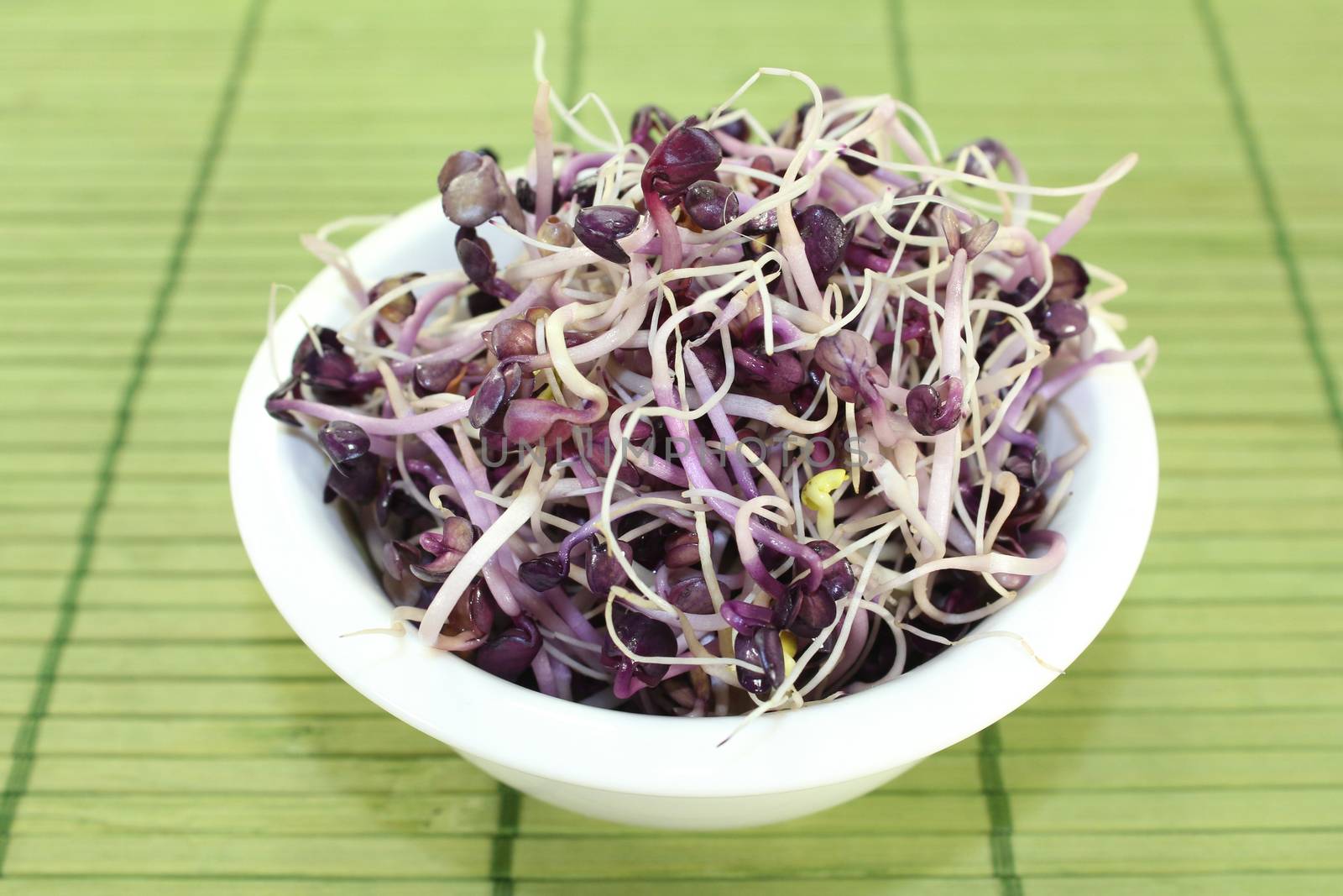 a bowl of radish sprouts on a bast mat