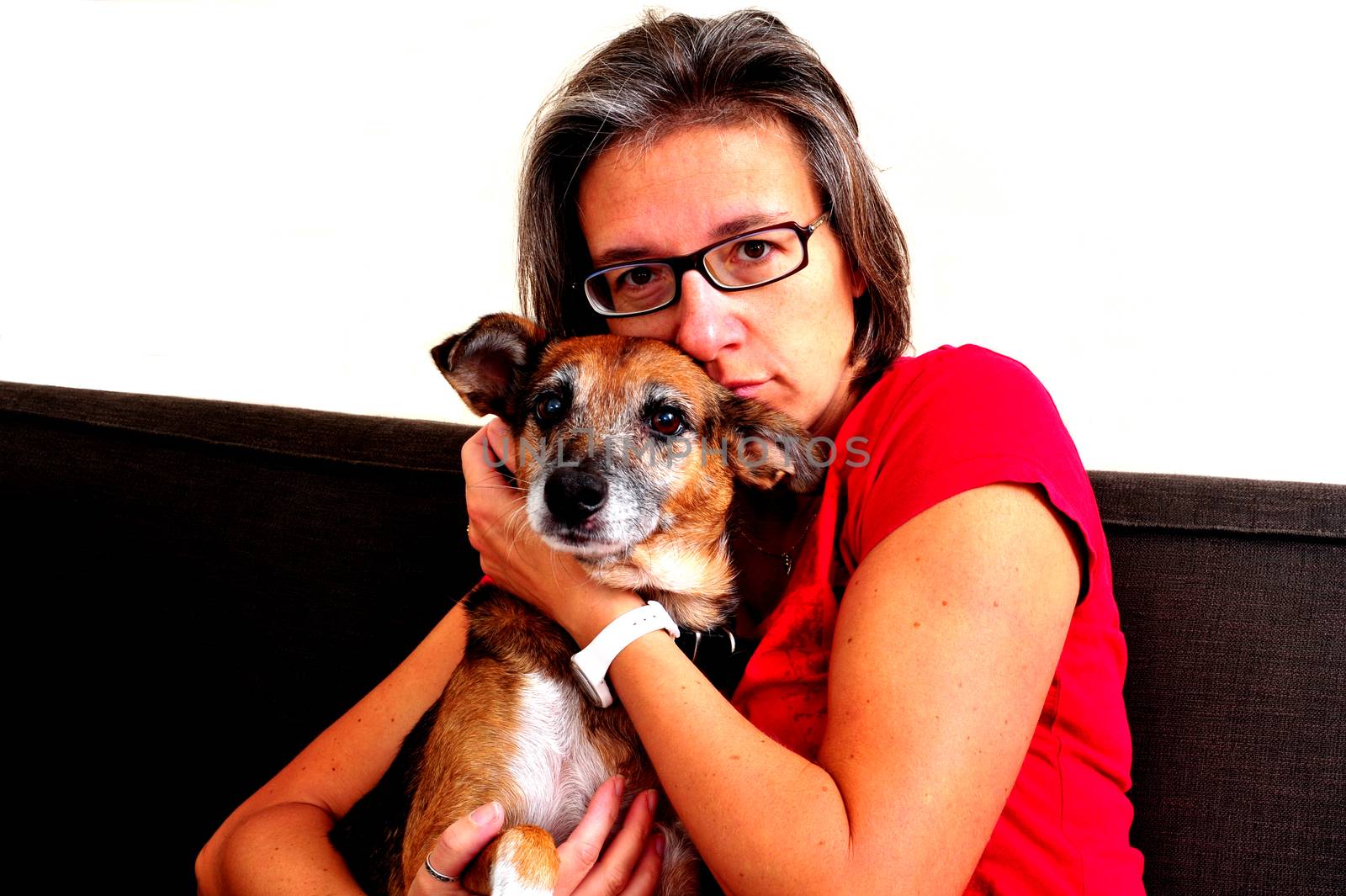A Woman cuddling with dog on a grey sofa