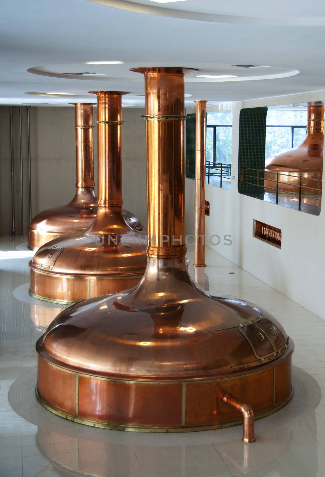 Line of three brewing vessels in brewery. by Claudine