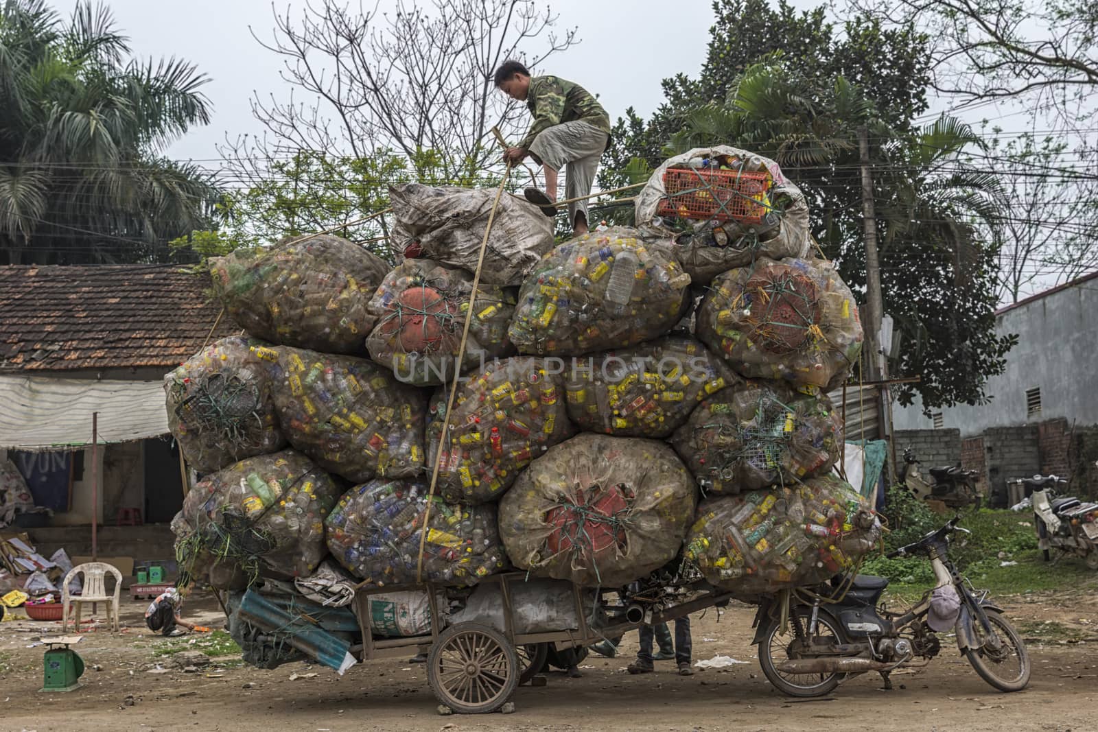 HANOI, VIETNAM - CIRCA MARCH 2012: Recycling cans and bottles loaded on cart behind motorbike. Voluminous colorful and amazing proposition.