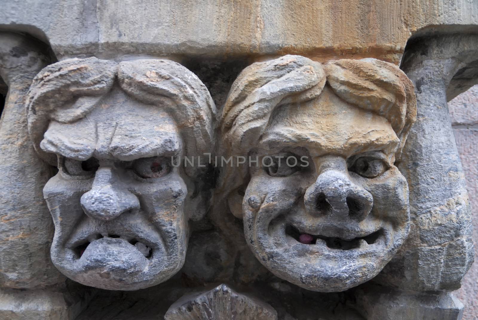 Fresco of angry and happy male's face set in stone. by Claudine