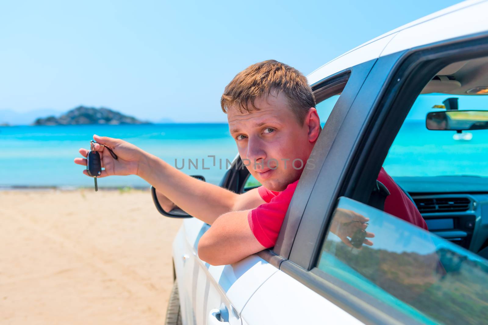the man with the keys to the car looks out the window on the background of the sea