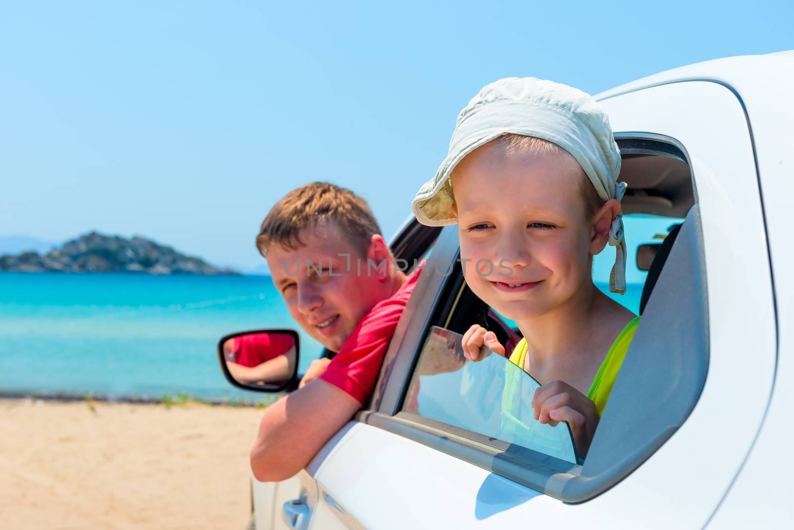 little boy and his father in a car on the beach