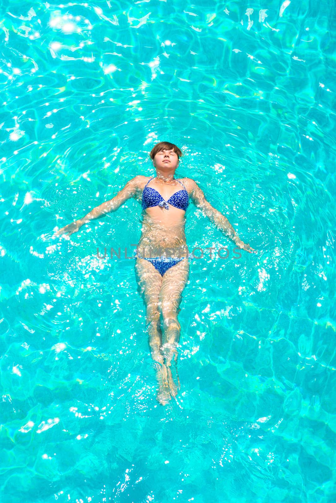 young girl floating in the pool outdoors