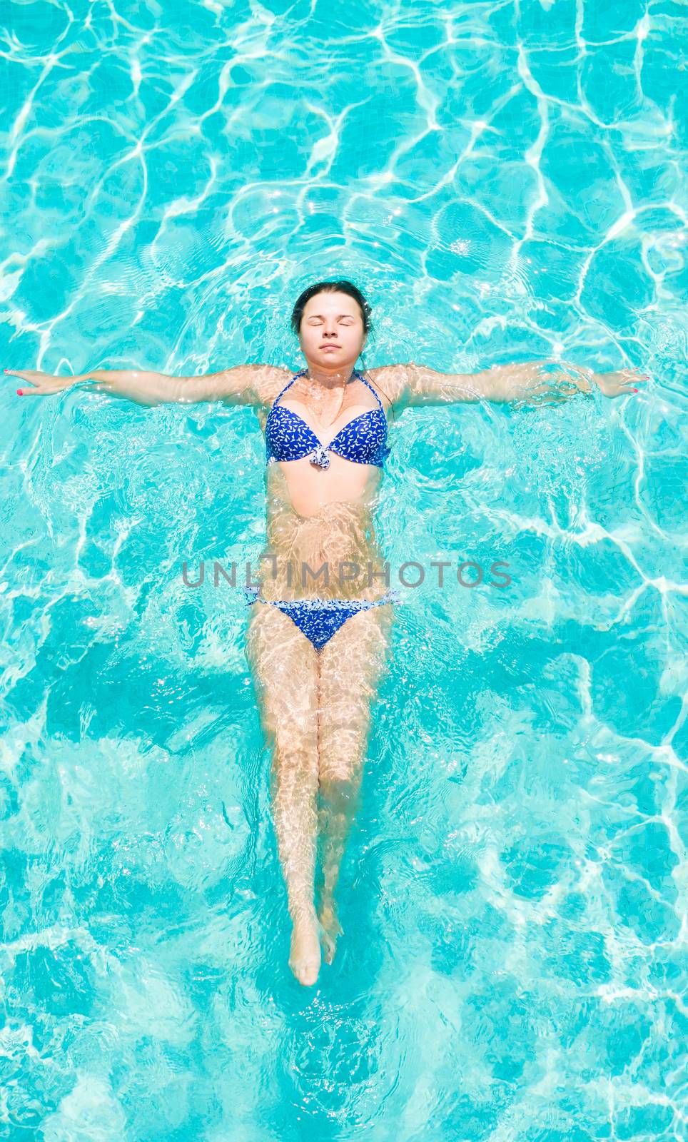 beautiful young brunette woman with closed eyes lying on the water