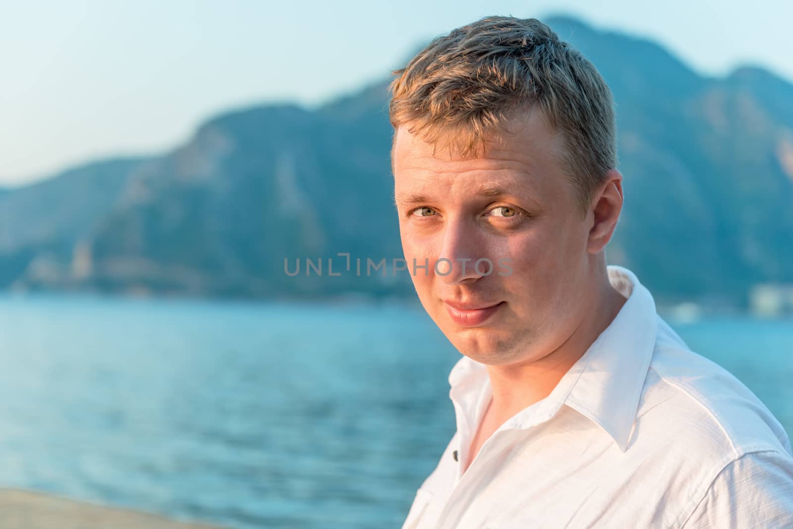 young and beautiful man on a background of sea and mountains