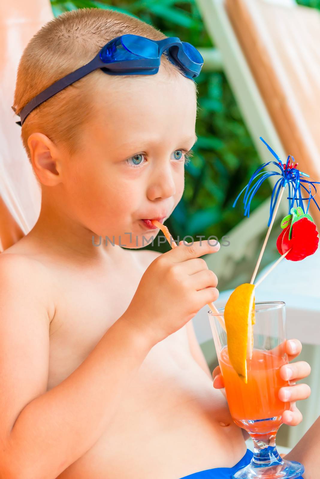 boy on a sun lounger beside the pool with cocktails