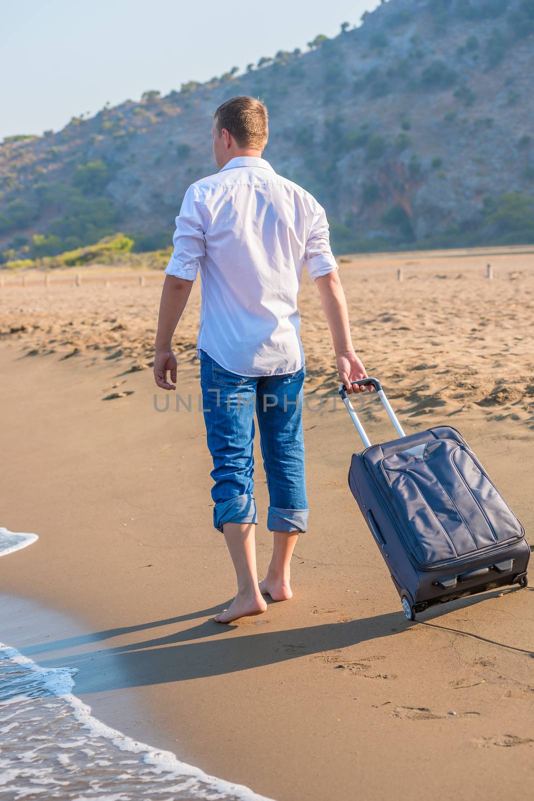 man with a suitcase walking along the beach