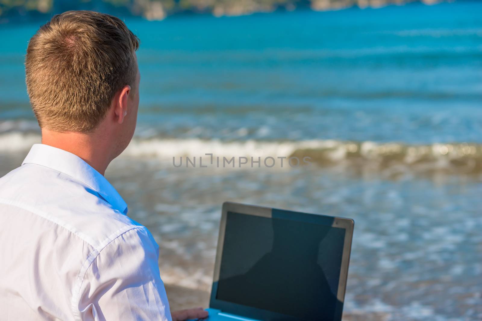 man with laptop at the sea rear view