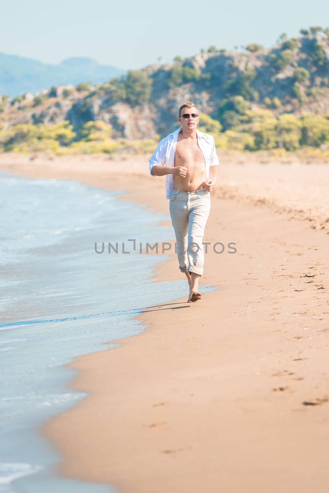 Vertical shot of the running men on the shore by kosmsos111