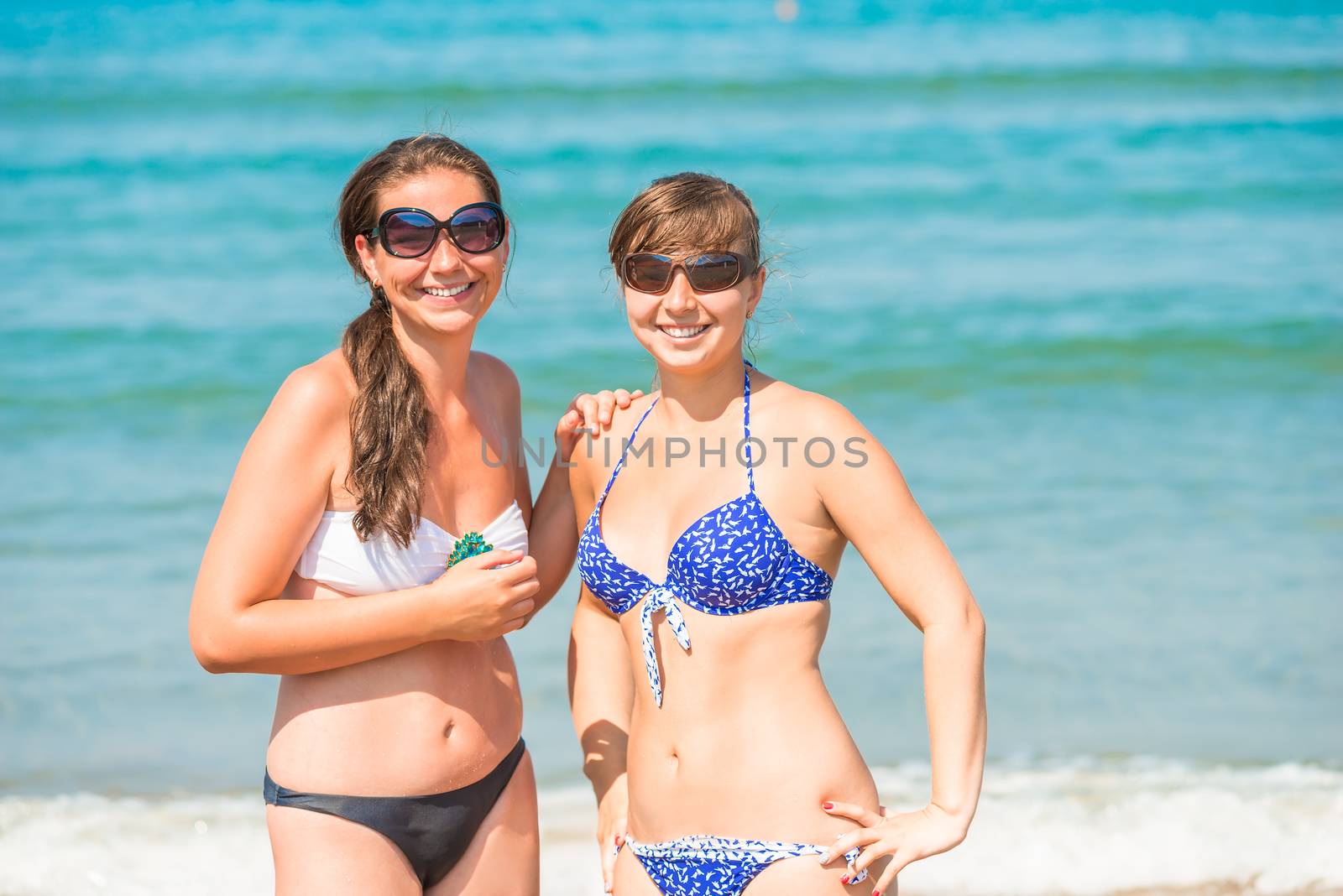 Two happy girls resting on the beach