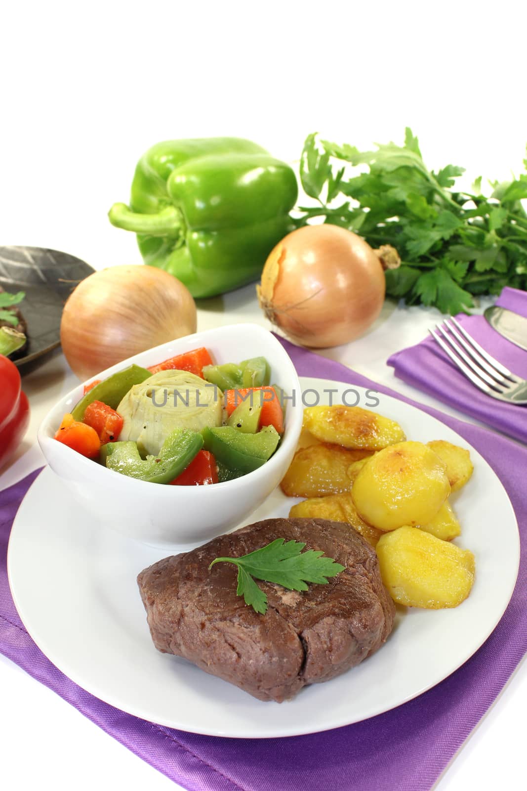 Ostrich steaks with baked potatoes and vegetables on bright background