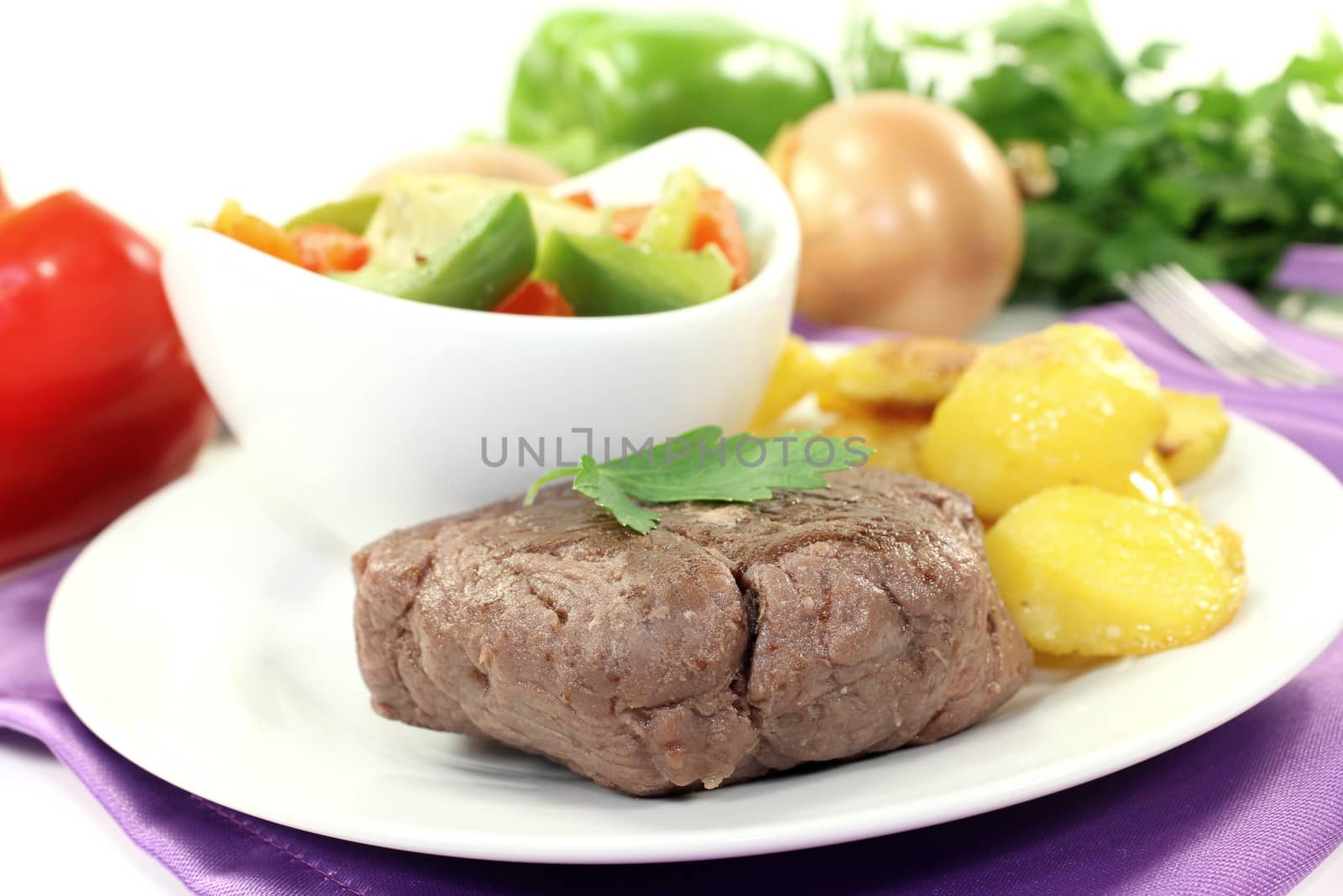 Ostrich steaks with baked potatoes and parsley on bright background