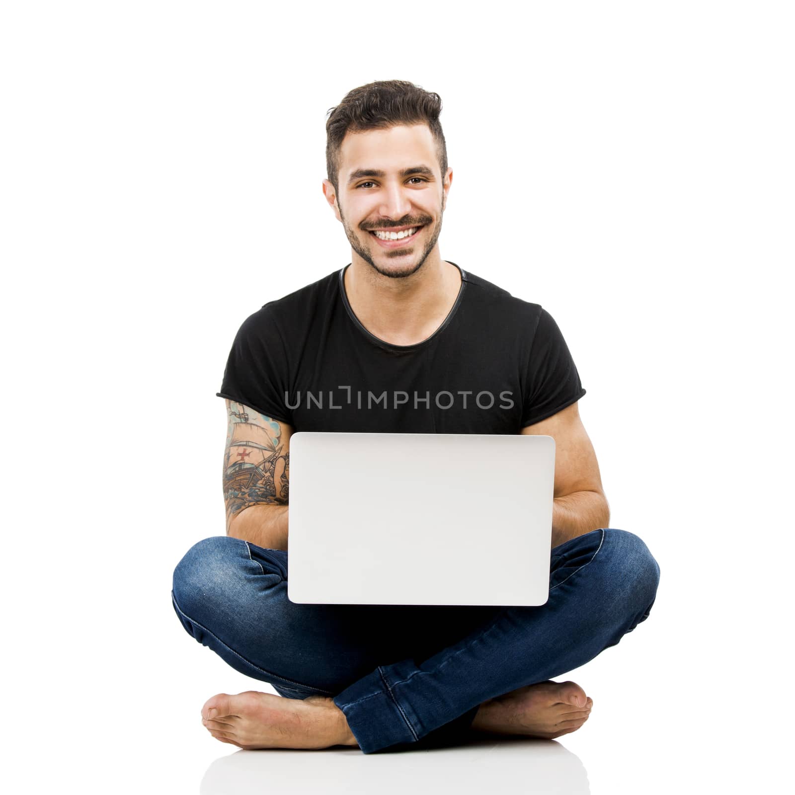 Latin man sitting on the floor and working with a laptop