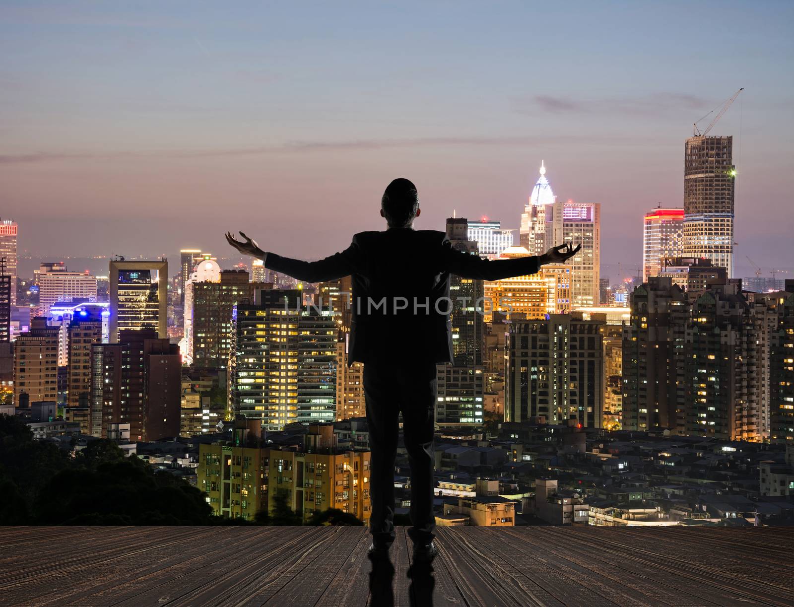 Silhouette of businessman open arms against city with copyspace.