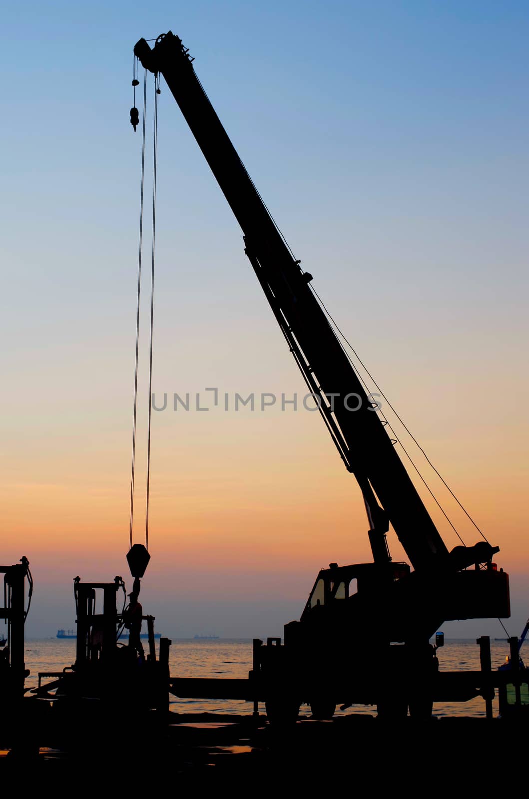 Silhouette crane working at port with sunset sky background