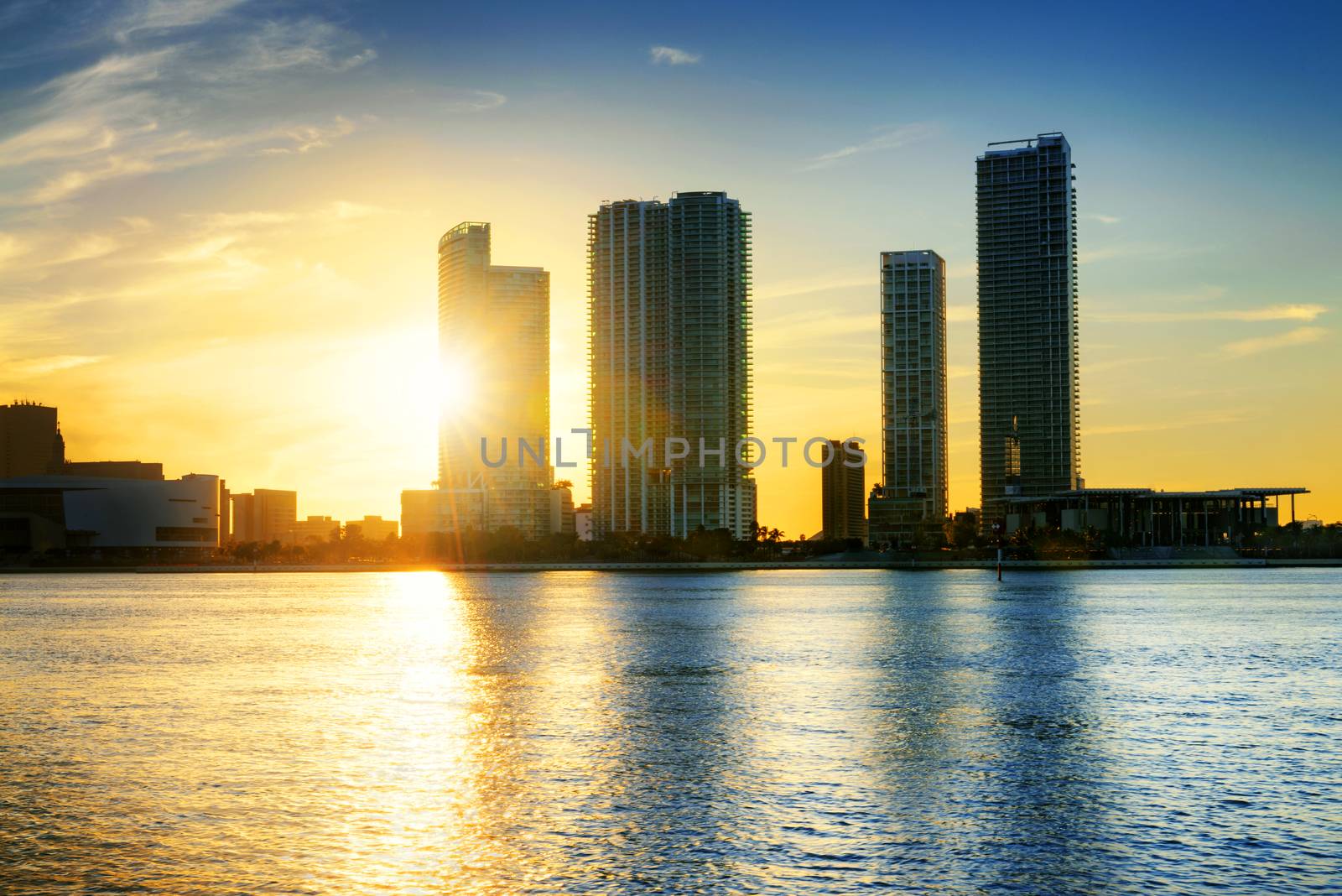 Miami city skyline panorama at dusk with urban skyscrapers over sea with reflection 