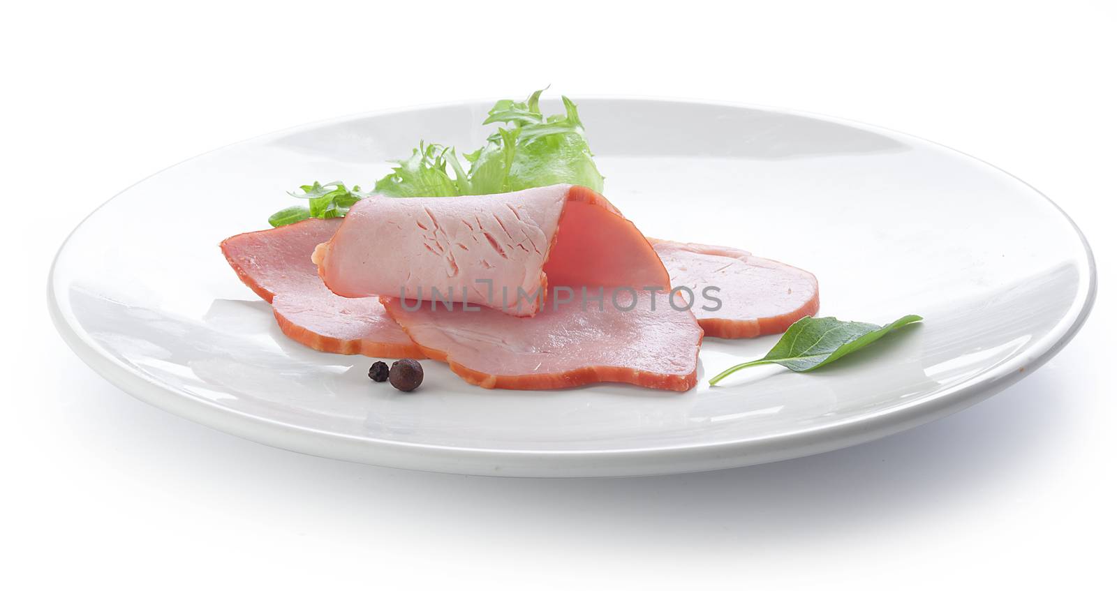 Two pieces of pork loin with fresh green lettuce and basil on the white plate