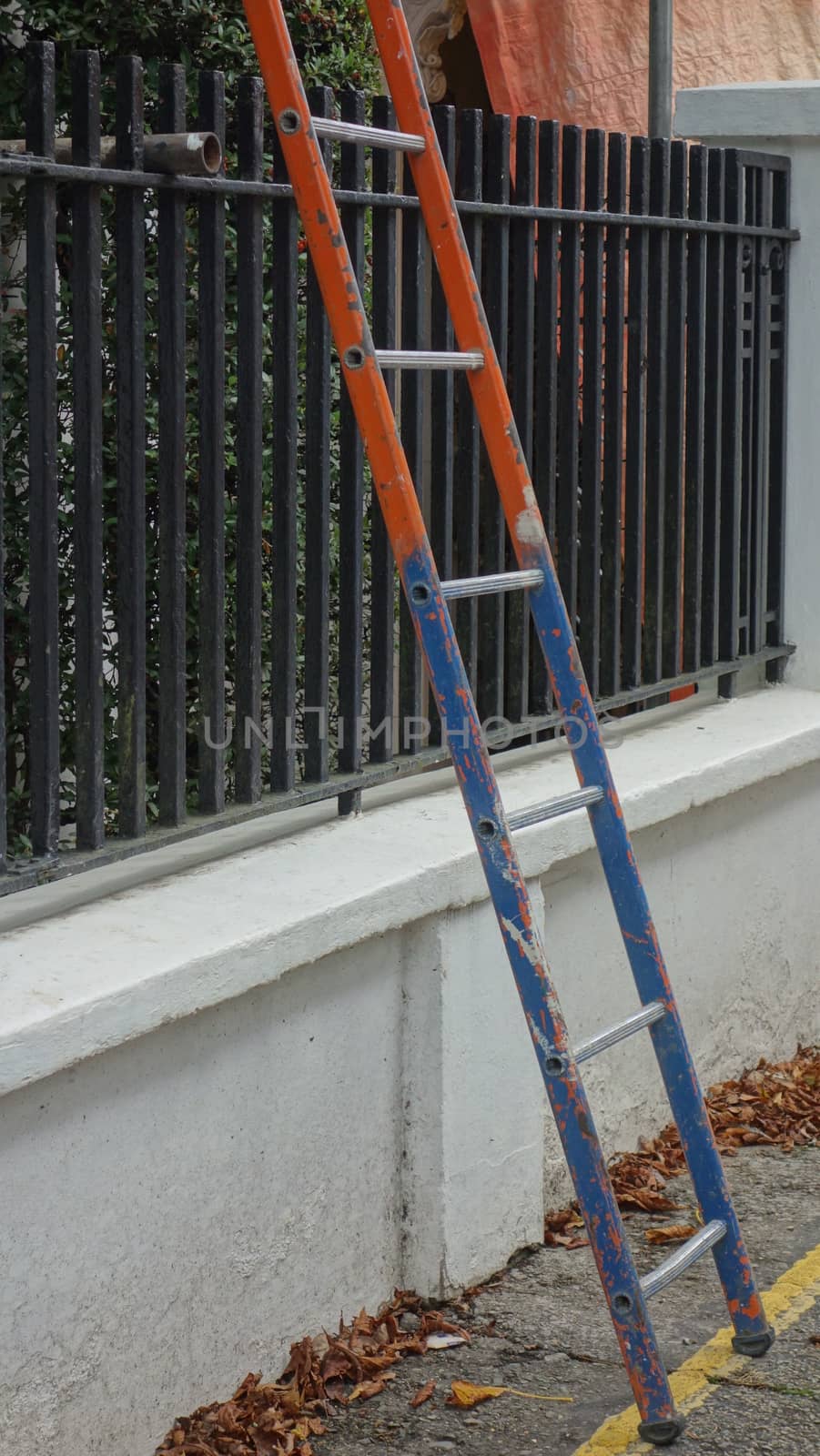 Blue and orange ladder leaning against a building