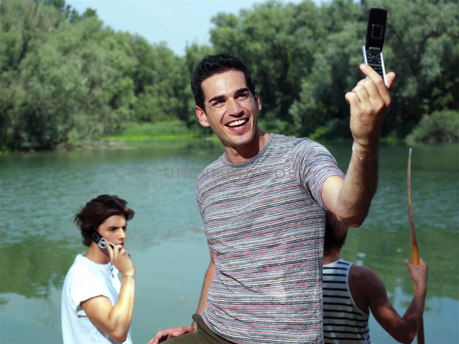 Handsome young guy taking photo with cellphone in park - Outdoor 