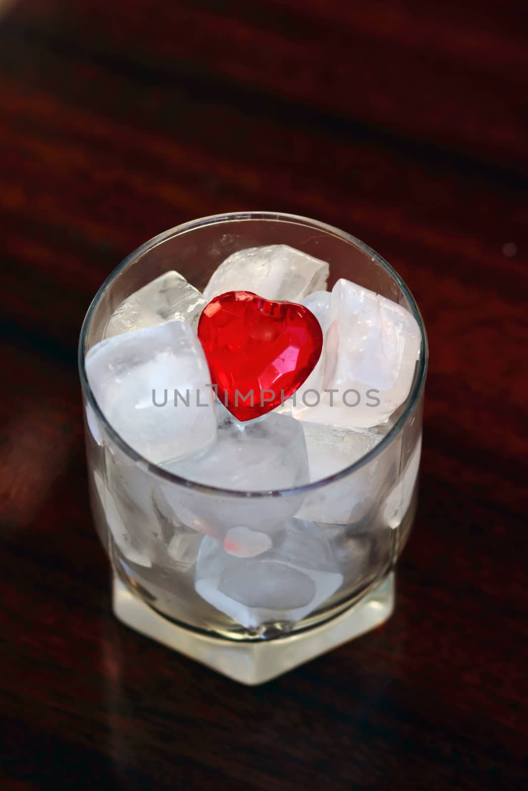 Red heart in glass with the cubes of ice