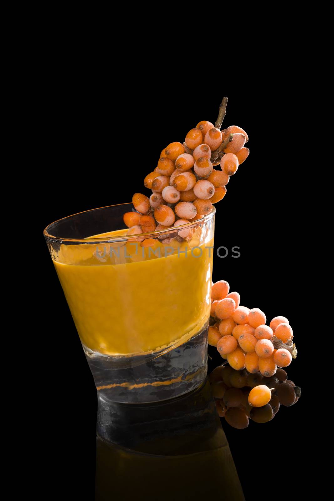 Sea buckthorn and sea buckthorn juice in glass isolated on black background. Healthy living, immune system booth.