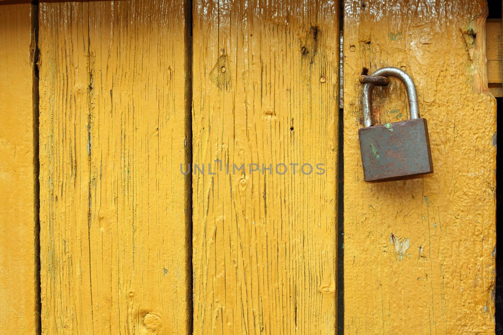 padlock on yellow wooden door by taviphoto